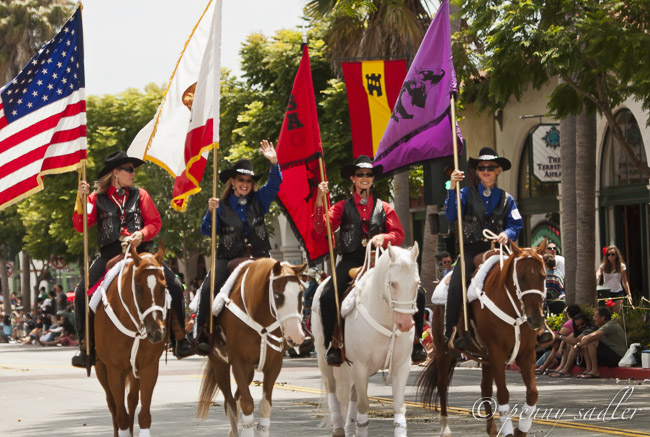 4 women on horseback. three brown horses and one white horse. The Fiesta Old Spanish days parade.