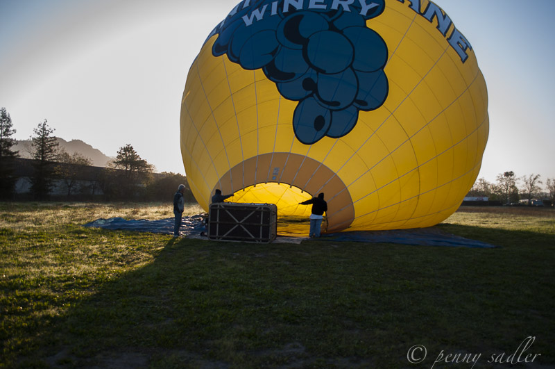 yellow and blue balloon laying on side while filling with air.