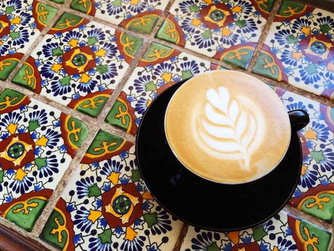 coffee with artistic foam on a colorful tiled tabletop