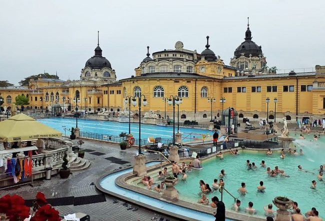 Yellow art nouveau building and swimming pool at The Szechenyi baths in Budapest.