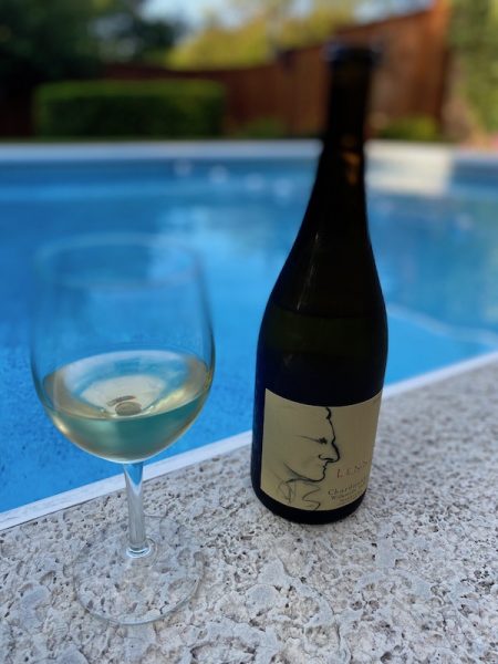 White wine in glass and bottle by swimming pool