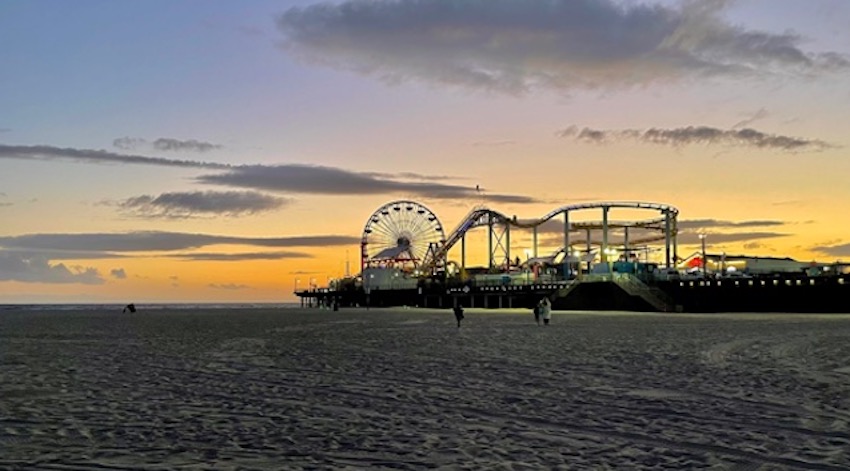 Santa Monica beach with the historic ferris wheel and pier in the background at sunset.