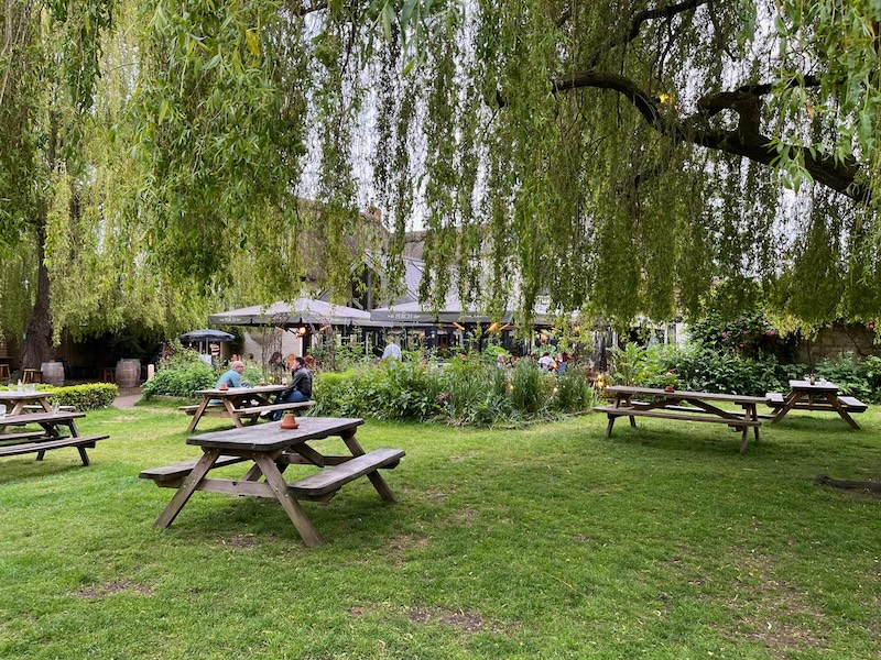 picnic tables under the willow trees beside Isis in Oxford, England.